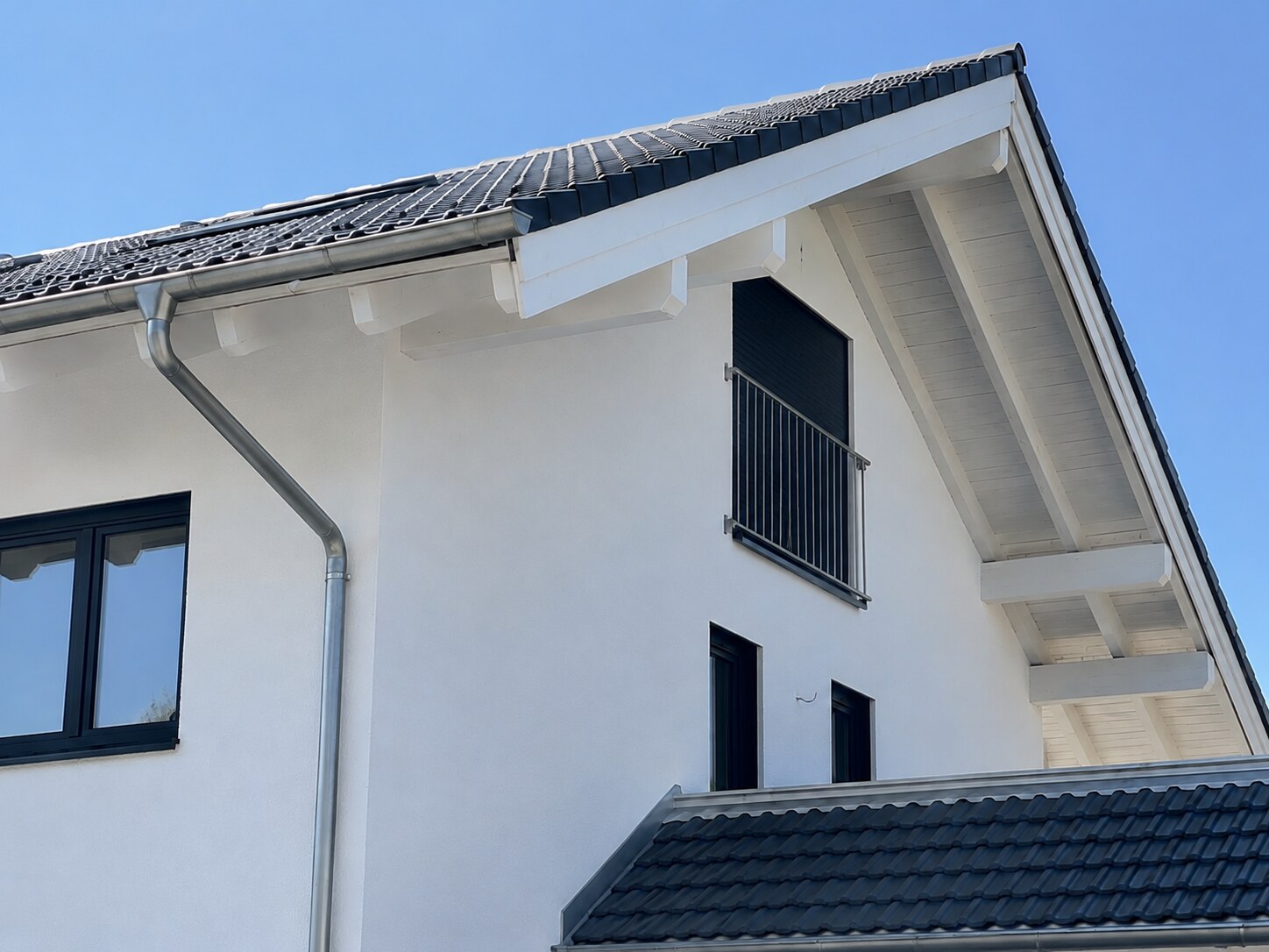 Architekturdetail der Doppelhaushälfte in Otterfing mit Giebel, Dachkonstruktion und dunklen Fensterelementen