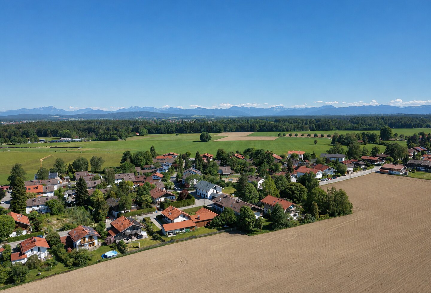 Luftaufnahme von Otterfing mit Wohngebiet, Feldern und Panorama der Bayerischen Alpen